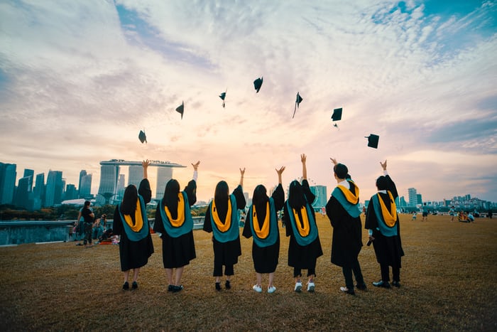 college graduates throwing hats in the air