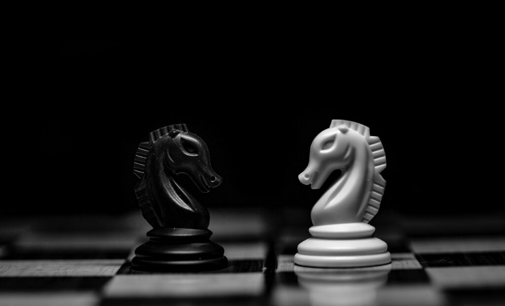 A chess board in the dark where two horses are facing one another